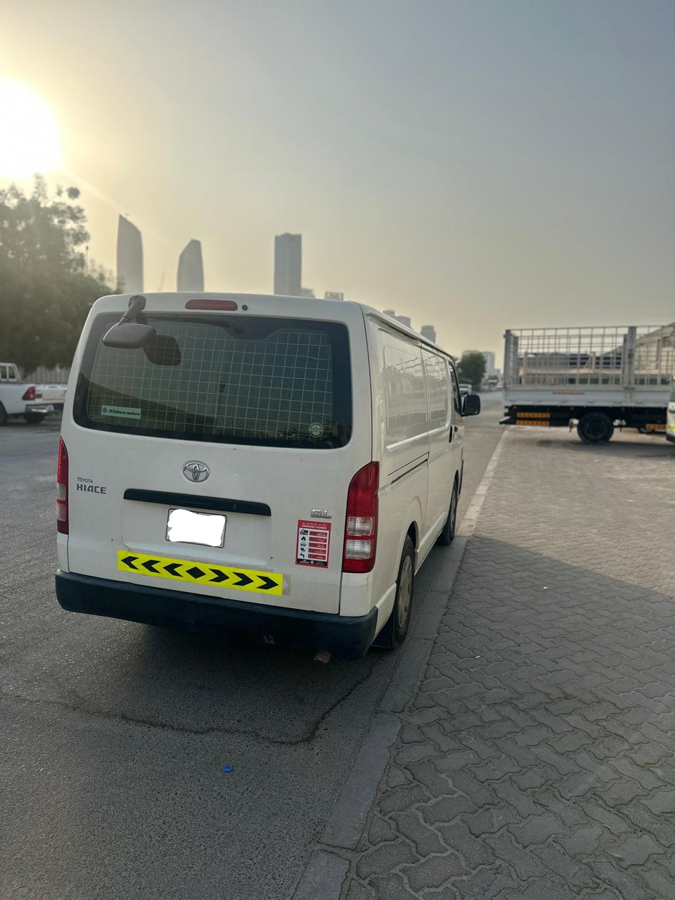 White Toyota Hiace van from Dubai Van Movers on a street with buildings in the background