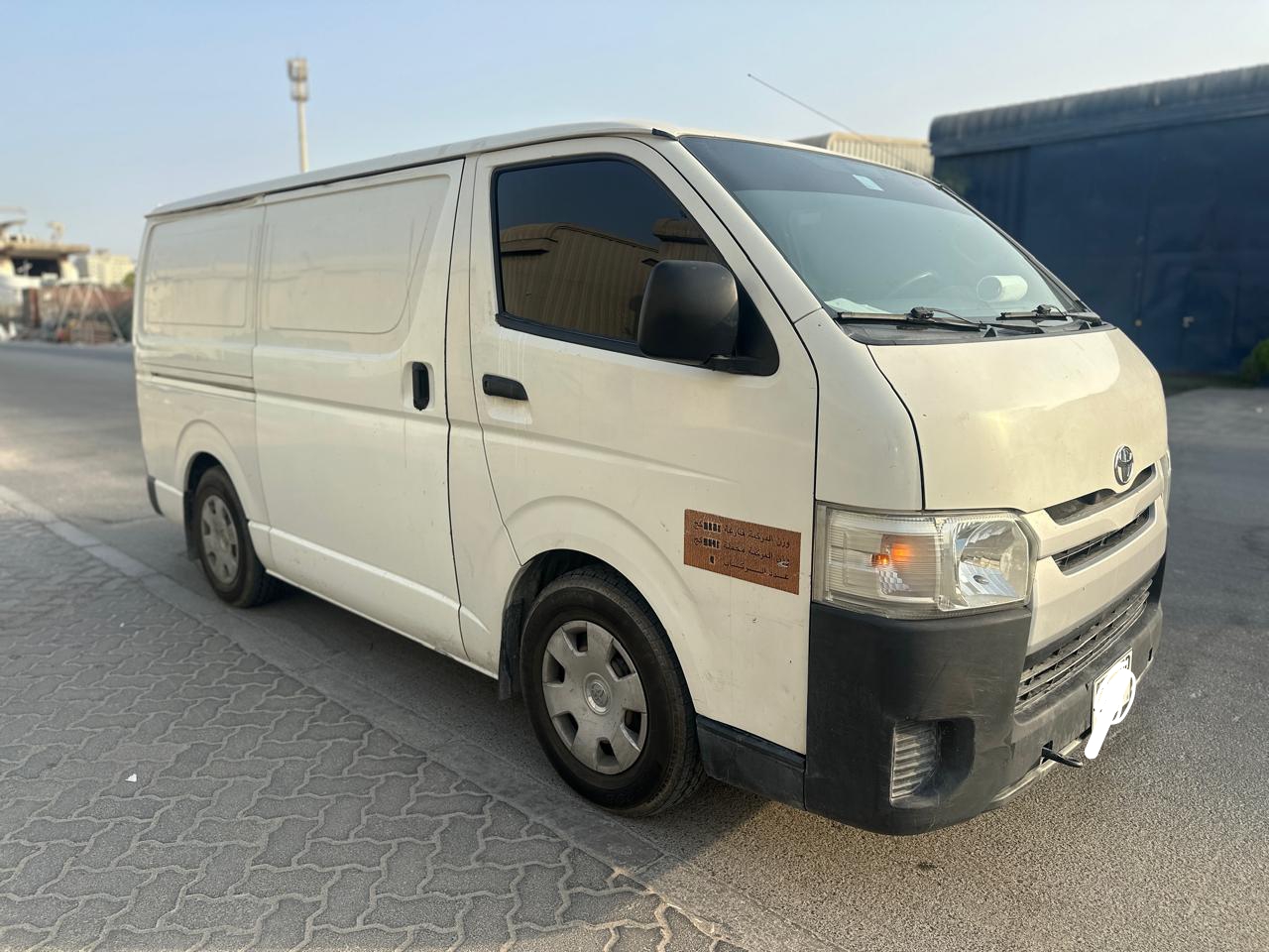 White Toyota Hiace van from Dubai Van Movers, side view with a driver's door open